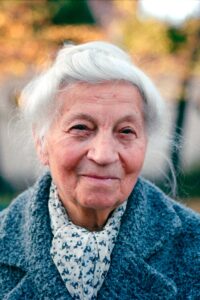Portrait of a smiling elderly woman outdoors in Kraków during fall.