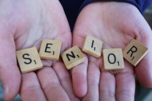Close-up of hands holding Scrabble tiles spelling 'senior'.