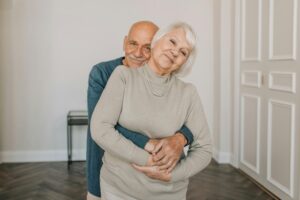 Heartwarming portrait of an elderly couple embracing happily indoors, showcasing love and companionship.