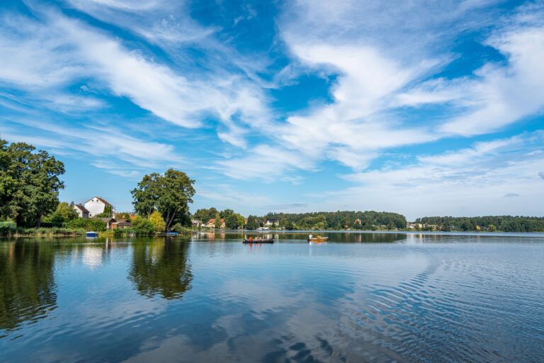 Tranquil view of a lakeside village with boats and reflections under a vibrant sky.