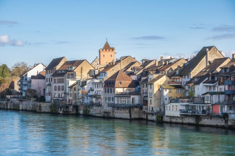 Scenic view of traditional European architecture by the river on a sunny day.
