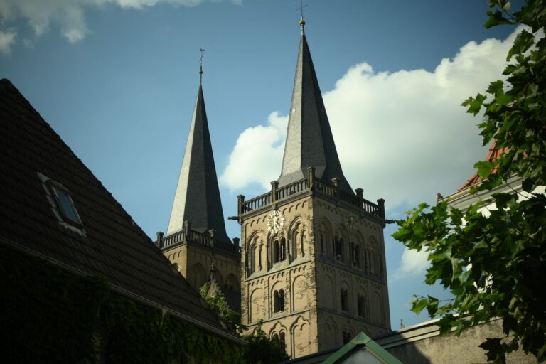 Low angle shot of gothic church towers with clear sky, featuring intricate architectural details.