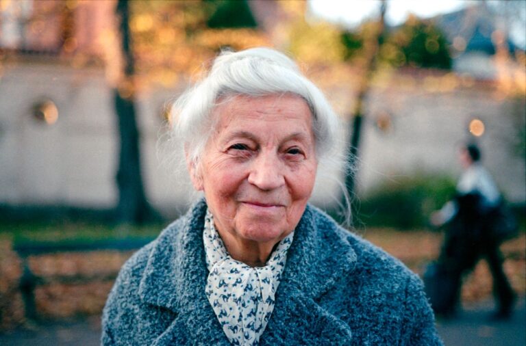 Portrait of a smiling elderly woman outdoors in Kraków during fall.