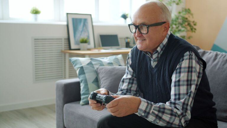 Senior man enjoys gaming on a cozy couch at home, creating leisure vibes.
