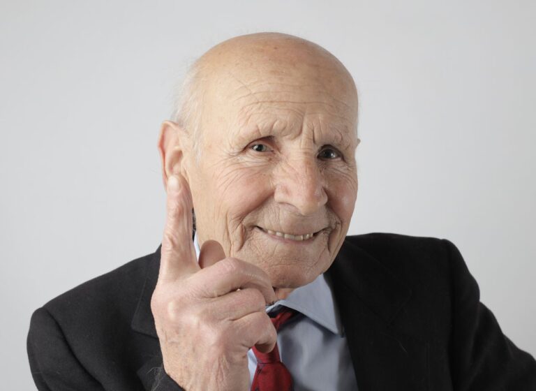 Charming portrait of a senior man smiling warmly in a suit with a confident gesture.